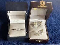 Jewelry boxes displaying sterling silver pearl earrings and a sterling silver ring with stones.
