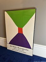Full view of the framed lithograph poster leaning on wall showing colorful abstract design and exhibition details.