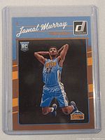 Front view of Jamal Murray rookie basketball card in protective sleeve, showing player in Denver Nuggets uniform mid-jump with basketball. Donruss and RC logos visible.