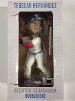 Front view of Teoscar Hernandez bobblehead figurine inside its packaging, showing the player in batting pose with baseball bat and helmet.