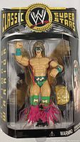 Front view of Ultimate Warrior figure in sealed packaging with championship belt visible.