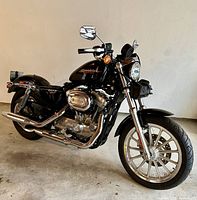 Left-side view showing black fuel tank with Sportster logo, chrome engine and exhaust, silver front wheel.