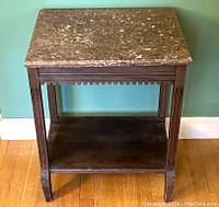 Front view of the antique wooden stand table with brown marble top and lower wood shelf showing fluted legs and battlement shaped apron.