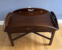 Butler's tray table with both side leaves folded up showing brass hinges and cutout handles.