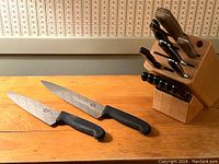Photo showing full butcher block with knives including large chef knives and utility knives.