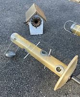 Photo showing one of two squirrel-safe standing bird feeders and the small chickadee house on asphalt ground.