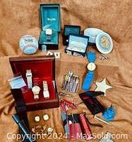 Overview of lot arranged on brown fabric: watches in boxes, Mr. Peanut figure, cufflinks, tool kits, knives, flashlights, baseball, dish