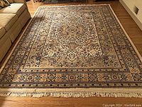 Full view of rug laid out on hardwood floor between sofa and chair.