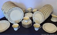 Full set of Lenox Windsong china laid out showing all plates, saucers, cups, and creamer in excellent condition with consistent floral and silver design.