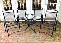 Full set of one round table and four chairs shown outdoors on brick patio.
