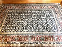 Large rectangular Turkish rug in blue, rust, and cream laid flat showing full pattern and border.