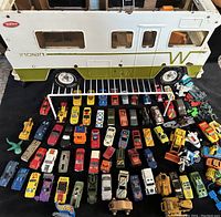 Wide view showing large collection of vintage metal toy cars and vehicles arrayed in front of the Tonka Indian Winnebago RV, showcasing variety and quantity.