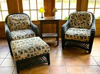Full view of seating set including two wicker chairs, ottoman, vintage oak table, lamp, and candle holder in enclosed porch.