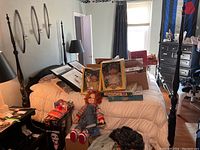 Full view of the queen size four post bed with various items on top including dolls and framed pictures, showing the overall bed structure and condition.