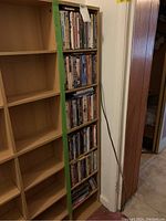 DVD selection stored on shelving unit shown with green tape label 'DVDs'. Shelf mostly full with DVDs vertically aligned showing spines.