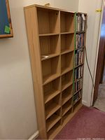 Front and side view of wood shelving unit designed for CDs or DVDs, showing empty rectangular compartments.