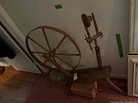 Full view of antique wooden spinning wheel on floor next to two sewing boxes.