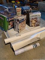 Photo showing multiple boxed baseball figurines including JoxBox, Jenga, Babe Ruth, and Joe DiMaggio. Rolled posters in foreground.