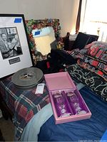 Framed photograph of Walt Disney, Disney MGM Studios tin, duffel bag, pillows, and wine glasses on a bed