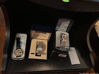 Three watches displayed: Looney Tunes watch with leather strap, Seiko Quartz digital watch in box, and Pulsar men's bracelet watch in box with tags.