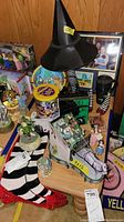 Multiple Wizard of Oz themed items including black lamp with witch's legs and striped stockings, red shoes, figurines on carriage, colorful tin, and framed pictures.
