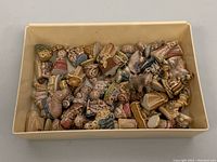 Full view of over 25 assorted WADE porcelain miniature figurines in a box, viewed from above showing varied shapes and sizes.