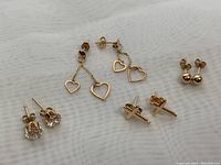 Four pairs of gold earrings laid on fabric background