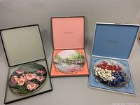 Three Royal Doulton collector plates in original boxes showing the floral and landscape designs
