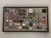 Top down view of 50+ assorted costume rings on foam display tray showing a variety of shapes, colors and styles