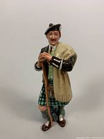 Front view of Royal Doulton porcelain figurine The Laird HN 2361 showing man in Scottish attire with walking stick.