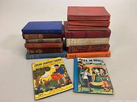 All antique books stacked showing variety of colors, sizes, and bindings.