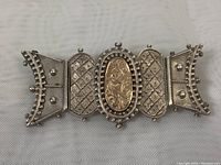 Front view of an ornate old gold and sterling silver religious brooch showing detailed metalwork and central gold inset.