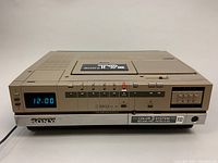 Front view of the Sony SL-T9ME BetaMax VCR showing clock display reading 12:00, control buttons, and Sony branding.
