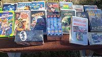 Photo displaying 22 VHS family titles spread out on a surface including various well-known characters and titles such as Muppets and Superman.