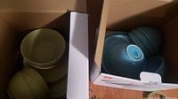 Box with sage green dishes including plates and bowls, and a box with robin's egg blue bowls in the photo.