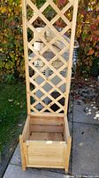 Front view of one wooden garden box showing the lattice trellis and planter box base in natural wood finish.