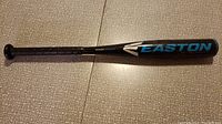 Full view of the black and blue Easton aluminum child's baseball bat with grip tape on the handle and the Easton logo on the barrel.