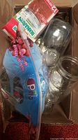 Box showing some clear glass jars and a pack of Bernhard red jar bands