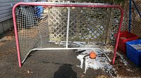 Front view of the full size street hockey net with pink frame on asphalt.