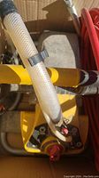 Close-up of the yellow and black Wagner ProCoat paint sprayer with attached clear hose and red control knob.