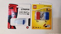 Photo of Kingston 64GB DataTraveler 50 USB flash drive unopened in packaging alongside LEGO 2-pack USB flash drives (8GB each) in red and blue.