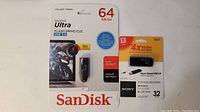 Photo shows unopened SanDisk Ultra 64GB USB 3.0 flash drive and Sony 32GB USB 3.0 flash drive in package.