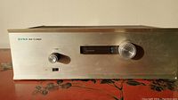 Front view of Dynaco FM tuner showing aluminum panel with control knobs and tuning display.
