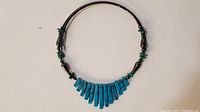 Full view of turquoise necklace showing fan-shaped blue stones and alternating green and hematite beads