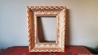 Front view of ornate gold decorative rectangular picture frame with detailed leaf and scroll patterns, showing inner rectangular opening for artwork or photo