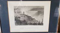 Framed black and white engraving of Niagara Falls with matting and frame visible, showing the engraving including text below image.