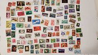 Photo showing a wide range of loose postage stamps from various countries spread out on a white surface