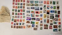 Photo of an assortment of loose postage stamps arranged in rows and columns, showing a variety of colors, designs, and cancellations.