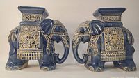 Front view of the pair of blue-glazed ceramic elephants facing each other, showing raised trunk and decorative detailing.