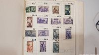 Photo of a stamp album page showing Italian stamps arranged with catalog numbers, mostly purple, green, brown and red stamps.